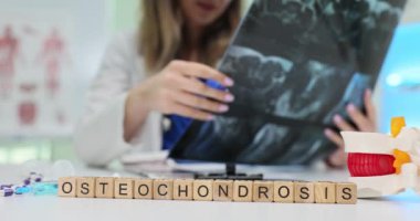 Osteokondrosis ile ilgili röntgenleri inceleyen bir tıp uzmanı, sağlık ve teşhisi vurguluyor..