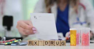 Bir sağlık uzmanı ofiste reçeteyi gözden geçirir ve masada ilaç bulunur.
