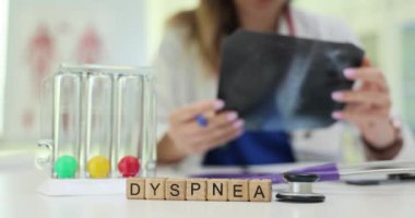 Bir doktor, yanında laboratuvar örnekleri olan dispne semptomlarını değerlendirirken hastaların röntgenlerini iyice analiz eder.