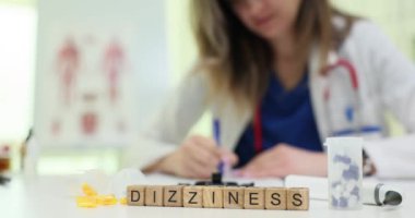 Bir sağlık görevlisi, hastaların baş dönmesinin semptomlarını renkli Scrabble fayanslarıyla belirterek tıbbi analiz gösteriyor.