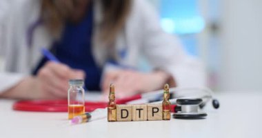 Kendini işine adamış bir sağlık çalışanı DTP aşısını stetoskop ve hasta güvenliği için şişelerle hazırlıyor.