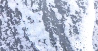 Kıyı şeridine yakın nemli kumda yazılmış büyük bir kelime. Su sahili sular altında bırakır ve harfleri siler. Yumuşak kuma kazınmış bir yazı.