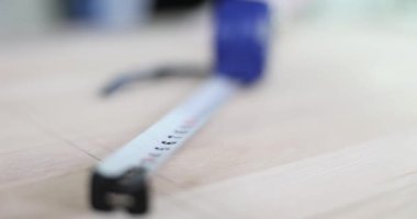 Rulet şeklinde şerit mezura cilalanmış ahşap yüzeyde bulunur. Mavi şerit ölçü bir sonraki ölçüm için hazırlanıyor