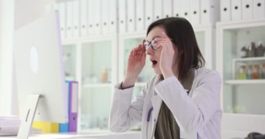 Gözlüklü kadın doktor bilgisayar ekranına bakıyor ve şaşırıyor. Şaşırmış doktor beklenmedik laboratuvar sonuçlarını okudu. Yavaş çekim