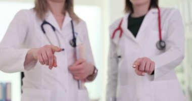 Beyaz önlüklü kadın doktorlar doğrudan kamera lensini gösteriyor. Profesyonel doktorlar izleyicileri sağlıklı kalmaya teşvik eder. Yavaş çekim