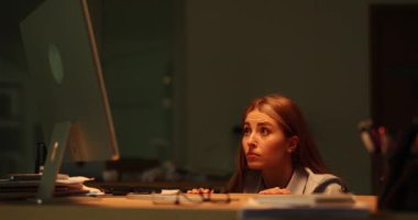 Korkmuş kadın elleriyle ağzını kapatarak masadan dışarı bakıyor. Bayan şirket çalışanı, ofis altında saklanan yıldırımlar nedeniyle korku yaşıyor.