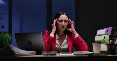 Yorgun kadın ofis çalışanı iş yerinde baş ağrısı çekiyor. Stresli kadın, ağır çekimde ağır iş yükü ile uğraşan tapınaklara dokunuyor