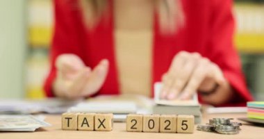 Vergi 2025, iş yerinde para sayan kadınlara karşı. Muhasebeci kadın yavaş çekim için hesap makinesi kullanıyor.