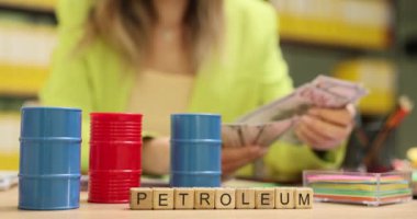 Para sayan iş kadınlarına karşı oyuncak varillerle oyuncak petroller. Girişimci, kârlı bir sektöre yatırım yapmak için nakit hazırlıyor