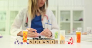 E vitamini küpleri ve klinikte ilaç düzenleyen kadın doktorla ilgili mesaj. Tıbbi uzman, ağır çekimde eczaneye odaklanmış hasta bakımı sağlıyor.