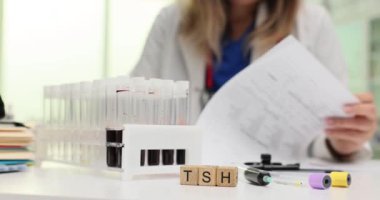 Tahta bloklarda TSH harfleri ve laboratuvarda çalışan doktorlara karşı kan örnekleri. Tıbbi uzmanlar test tüplerindeki numuneleri inceliyor.