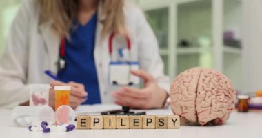 Doktor masasında insan beyni mankeni ve ilaçlı epilepsi var. Profesyonel nörolog, klinikteki hastayla hastalık tedavisini tartışıyor