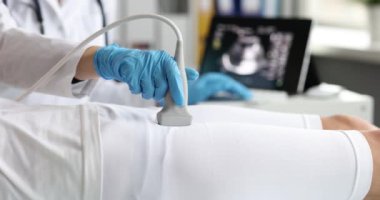 Eğitimli bir sağlık uzmanı, klinik ortamdaki bir hastanın kalçasında ultrason muayenesi yapar.
