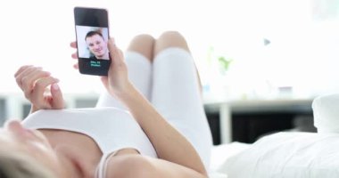 Parlak ortamında rahat bir yatakta rahatça dinlenirken bir insan video görüşmesinden zevk alıyor.