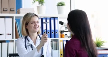 Parlak bir tıp bürosunda, bir sağlık uzmanı yakınlarda oturan bir hastanın gözlerini dikkatle kontrol eder.