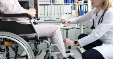 Şefkatli ve kendini işine adamış bir doktor, önemli tıbbi muayeneleri sırasında tekerlekli sandalyedeki bir hastaya yardım ediyor.