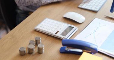 Hesap makinesi, madeni para ve temel kırtasiye malzemesi içeren temiz bir ofis masası, finansal görevler için ideal.
