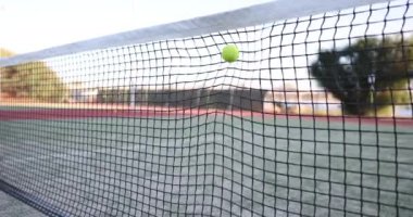 Şafak sökerken sakin bir kortu güzelce çerçeveleyen bir tenis ağının detaylı bir yakın çekimi.