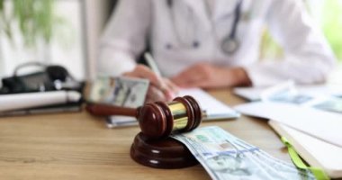 Tokmak ve yığınla parayla belgeleri inceleyen bir tıp uzmanı, karmaşık tıbbi sorunları sembolize ediyor.