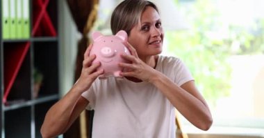 A joyful woman smiles with a piggy bank, symbolizing the importance of saving and financial planning