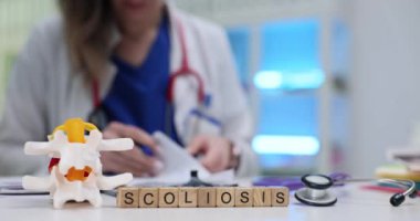 Bir tıp uzmanı anatomik modeller ve özel araçlar kullanarak kapsamlı bir skolyoz muayenesi yapar.