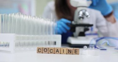 Kokain kelimesinin laboratuvar ekipmanlarının yanı sıra uyuşturucu analiz sürecini vurgulayan ayrıntılı bir yakın plan görüntüsü