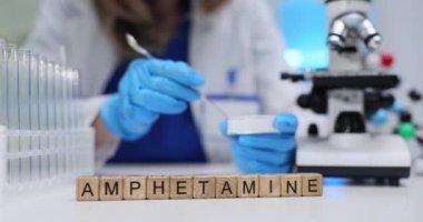 Kendini adamış bir bilim adamı, laboratuvarda mikroskop altında amfetamin maddelerini özenle analiz ediyor.