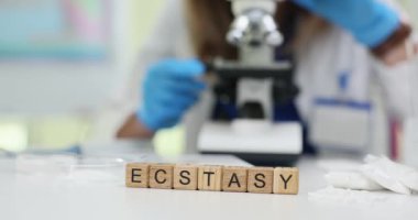 Yetenekli bir laboratuar teknisyeni, ecstasy 'yi mikroskop kullanarak titizlikle analiz eder.