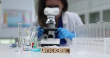Bir araştırmacı, laboratuvar ortamında mikroskop altında çeşitli eroin örneklerini dikkatle inceliyor.