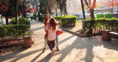 Mutlu kız güneşli bir günde şehir parkında annesine koşar. Neşeli kadın, hafta sonu ağır çekim buluşmasıyla tatmin olan çocuğa nazikçe sarılıyor.