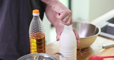 Profesyonel aşçı bir şişe sütü dikkatle açar. Becerikli aşçı evde krep yapmak için gerekli malzemeleri hazırlar. Yavaş çekim