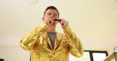 Profesyonel müzisyen mızıka ile duygusal bir melodi çalar. Işıldayan altın pullu ceketli adam yürekten mızıka çalıyor. Yavaş çekim