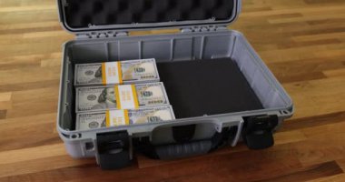 Dolar banknotları kademeli olarak metalik evrak çantasını dolduruyor. Asma kilit finansal gelişim için konteynır güvence altına alıyor. Parasal başarı inşa ediliyor.