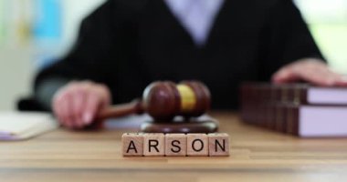 Yargıç tokmağı masaya koydu ve kundaklama davasında nihai kararı açıklamaya hazırlanıyor. Minyatür tahta bloklar, masada ARSON kelimesini oluşturur. Yavaş çekim