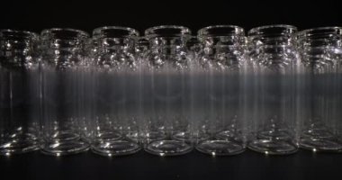 Steril laboratuvar tezgahına şeffaf cam kavanozlar düzgünce yerleştirilmiş. Cam kavanozlar siyah arkaplan deneylerinde bir sonraki kullanım için hazırlandı