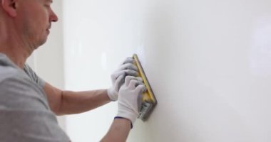 İnşaat işçisi elle zımparalanan pürüzleri temizliyor. Deneyimli inşaatçı düz ve cilalı duvar yüzeyi yaratır. Yavaş çekim