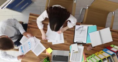 İş adamları finansal tablolar ve grafikleri gözden geçirmek için işbirliği yapıyor. Yönetici erkek ve kadın dizüstü bilgisayar ve belge kullanarak proje verilerini analiz ediyor
