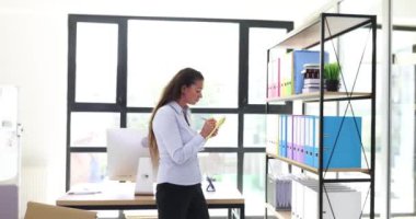 İş kadını, iş belgelerini raflarda düzenler ve ofiste beyin fırtınası yapar. Kadın modern ofis ortamında sunum hazırlıyor