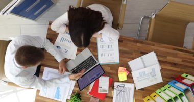 İş arkadaşları finansal verileri ve pazar eğilimlerini dizüstü bilgisayarla analiz ederler. Çalışanlar tabloda anlaşan grafikler ve grafikler üzerinde işbirliği yaparlar.