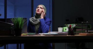 Yorgun Arap iş kadını tesettüre girmiş gece ofiste şiddetli bir baş ağrısı çekiyor. Müslüman kadın uzun çalışma saatlerinden sonra stresli ve yorgun.