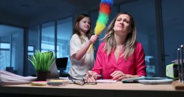 Genç kız, ofisinde renkli bir toz beziyle annesinin dikkatini dağıtıyor. Kadın şirket çalışanı, akşam ağır çekimde çalışırken sinir krizi geçirir.