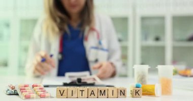 Doktorun ultrason araştırma sonuçlarını incelemesine karşı çeşitli ilaç ve kapsüllerle K vitamini. Tıp uzmanı sağlıklı yaşam tarzını teşvik ediyor.