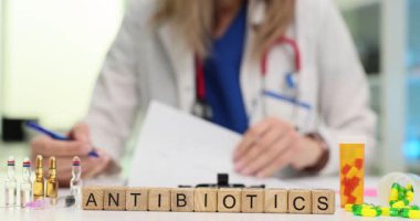 Tahta bloklara antibiyotik ve masadaki sağlık uzmanına mesaj at. Doktor hasta muayenesi sırasında ağır çekimde kayıtları doldurur.