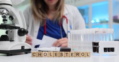 Tahta küplere kolesterol ve örnek araştırması yapan bir kadın. Tıbbi uzman, hastanedeki laboratuvar malzemeleriyle kan tahlili yapıyor.