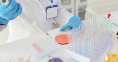 Laboratuvar çalışanı deney için mikro pipet hazırlıyor. Güvenlik üniformalı dikkatli teknisyen yavaş çekim araştırmasına hazırlanıyor.