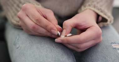 Kadın elleri koltukta oturan su toplayıcı paketten dikkatlice ilaç çıkartıyor. Kadın migrenle başa çıkmak için ilaç hazırlıyor.