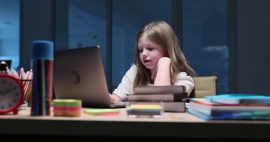 Güzel küçük kız akşam ev ödevi yaparken bilgisayarında görüntülü konuşma yapıyor. Sevimli liseli kızlar gece geç saatlerde okul işlerini hallederler.