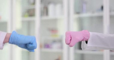 Lateks eldivenli doktorlar laboratuarda yumruk tokuşturuyor. Doktorlar hastane ortamında prosedürün başarıyla tamamlanmasını kutluyorlar