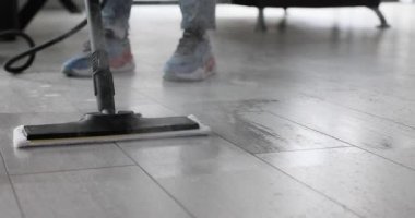 Temizlik işçisi döşemeleri temizlemek için buharlı paspas kullanır. İnsan, bakteri ve alerjiyi etkili bir şekilde ortadan kaldırmak için modern aletler kullanır. Yavaş çekim