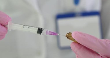 Deneyimli doktor şırıngaya reçeteli ilaç çekiyor. Doktor şırıngayı enjeksiyon için gerekli aşıyla dolduruyor. Yavaş çekim